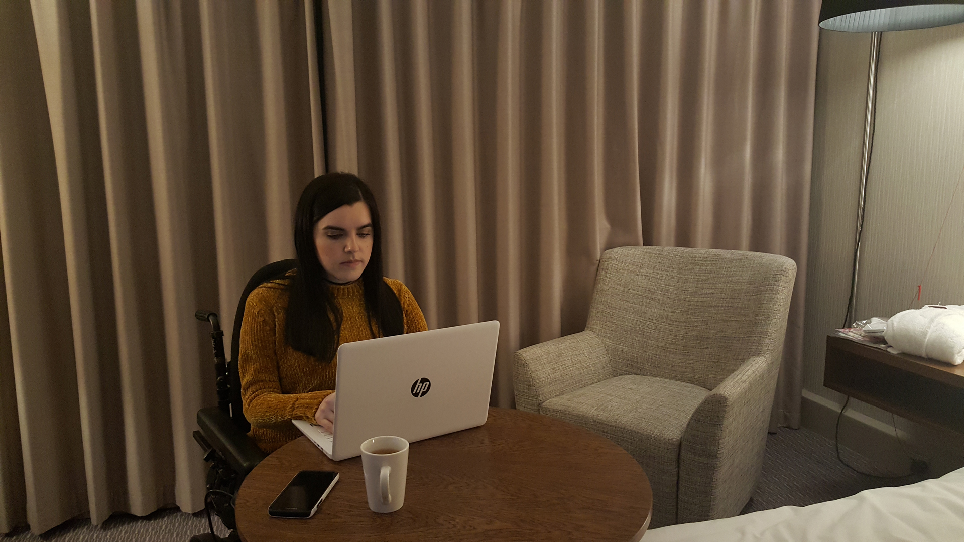 Emma working on her laptop in her Crowne Plaza Glasgow wheelchair accessible room