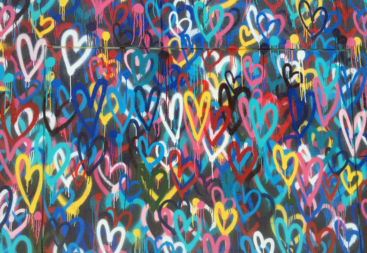 A wall covered in graffiti love hearts.