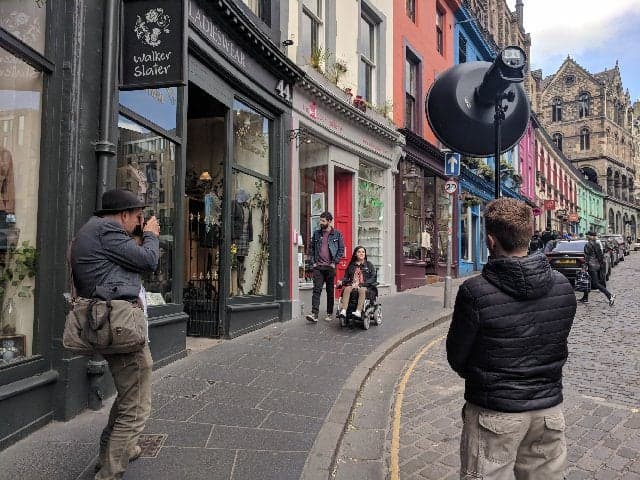 Things I've Loved in June: A behind the scenes photo of Emma and Allan during their photoshoot with VisitScotland. The photo shows Emma in her wheelchair and Allan on Victoria Street in Edinburgh with the photographer and lighting technician.