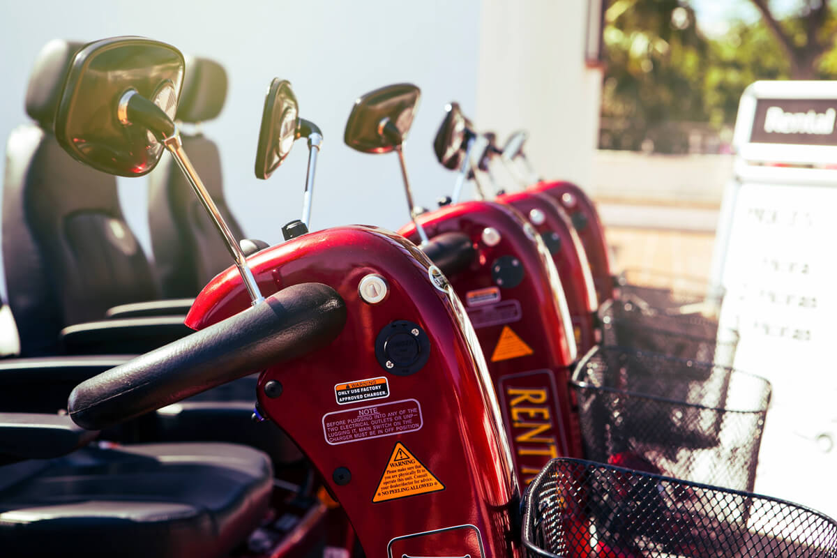 A close up of red mobility scooters lined up in a row.