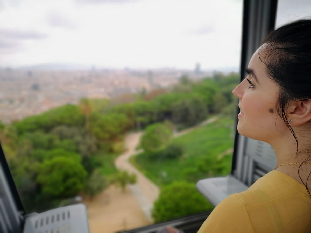 Emma is on Montjuïc Cable Car. She is looking out the window at the beautiful view.
