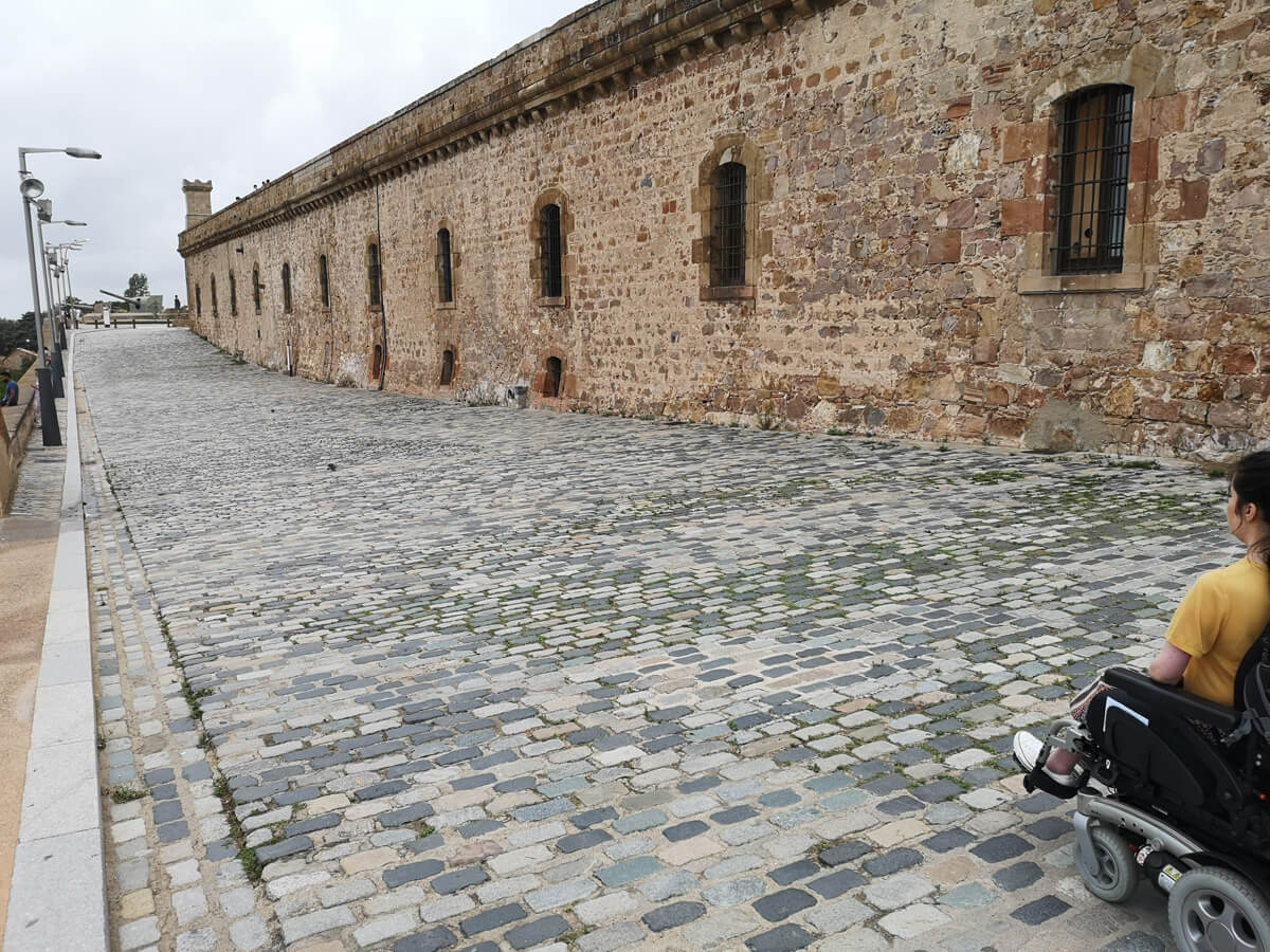 Emma driving her wheelchair along a cobblestone path around the grounds of Montjuïc Castle.