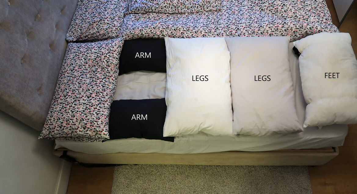Emmas kingsize bed showing her sleep system which consists of various pillows for her arms, legs and feet to prevent pressure sores.