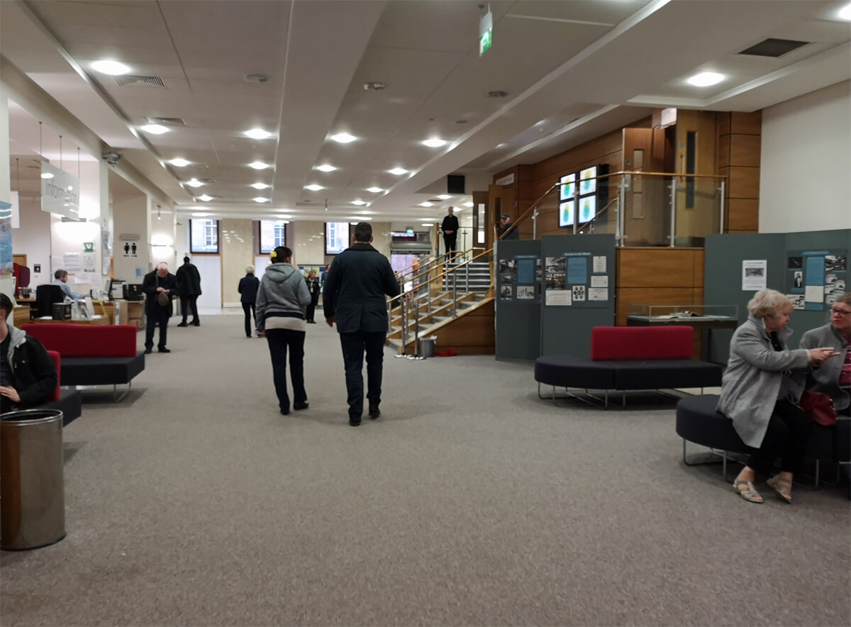 The foyer at the Mitchell Library. There are people walking around and sitting on seats.