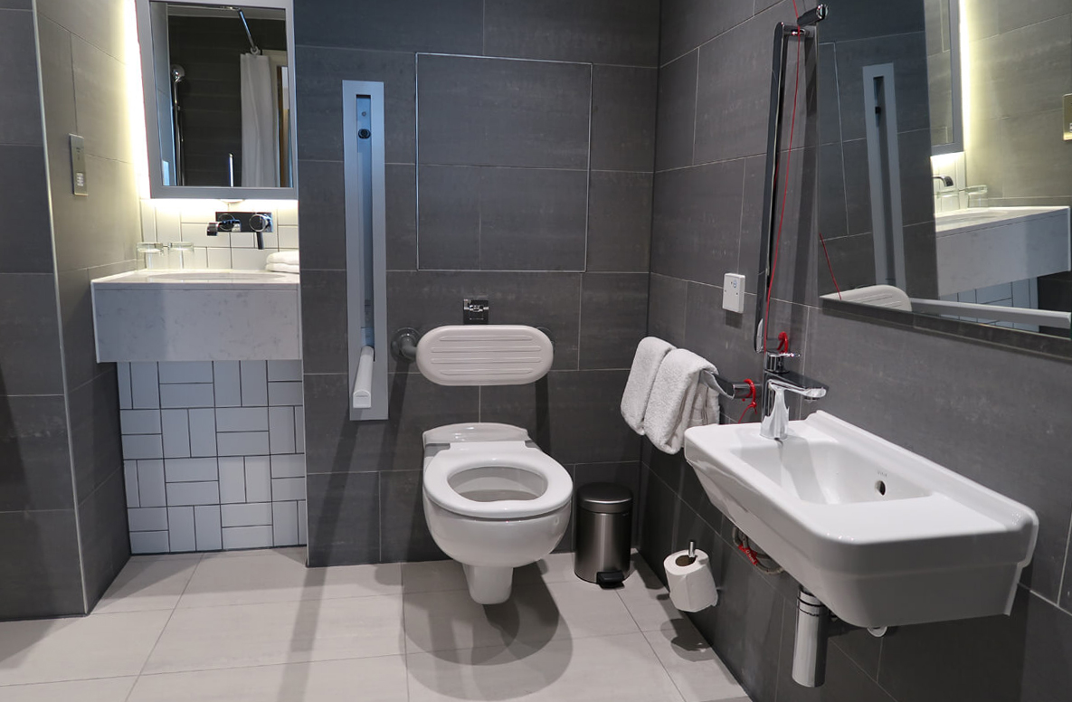 Toilet with grab rails and wash basin in our accessible hotel room.
