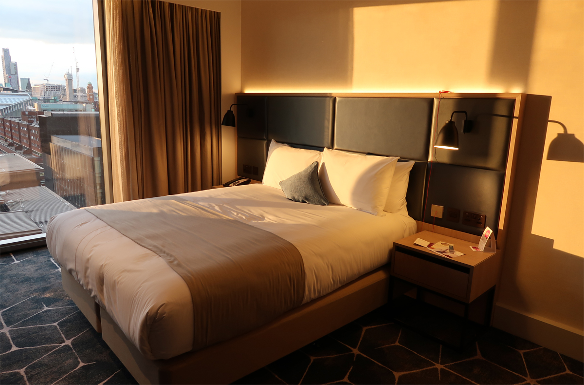 Close up of Queen sized bed when the golden sunlight is shining through the room.