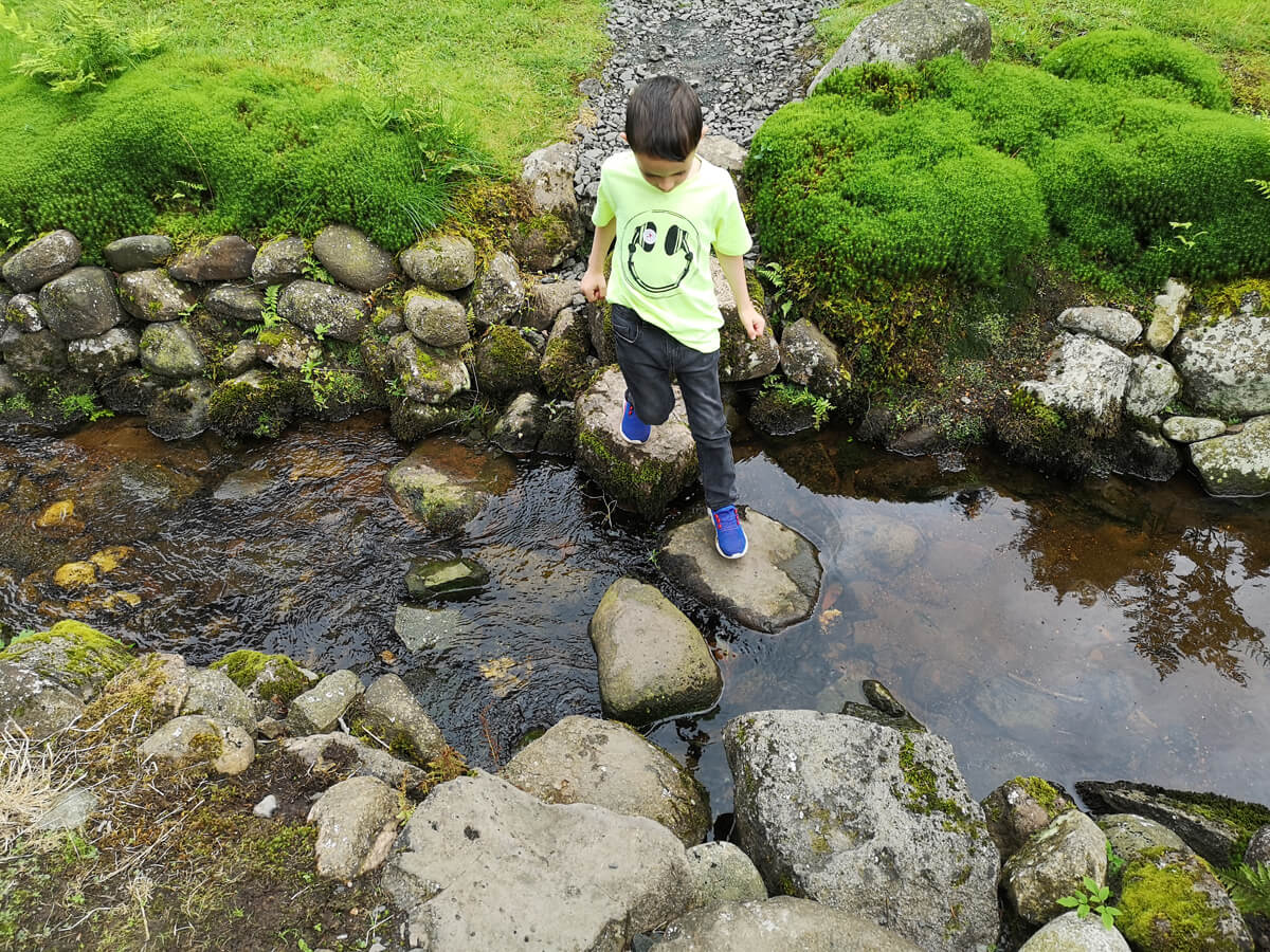 A little boy (Emma's nephew) crossing the stream by stepping on the stepping stones.