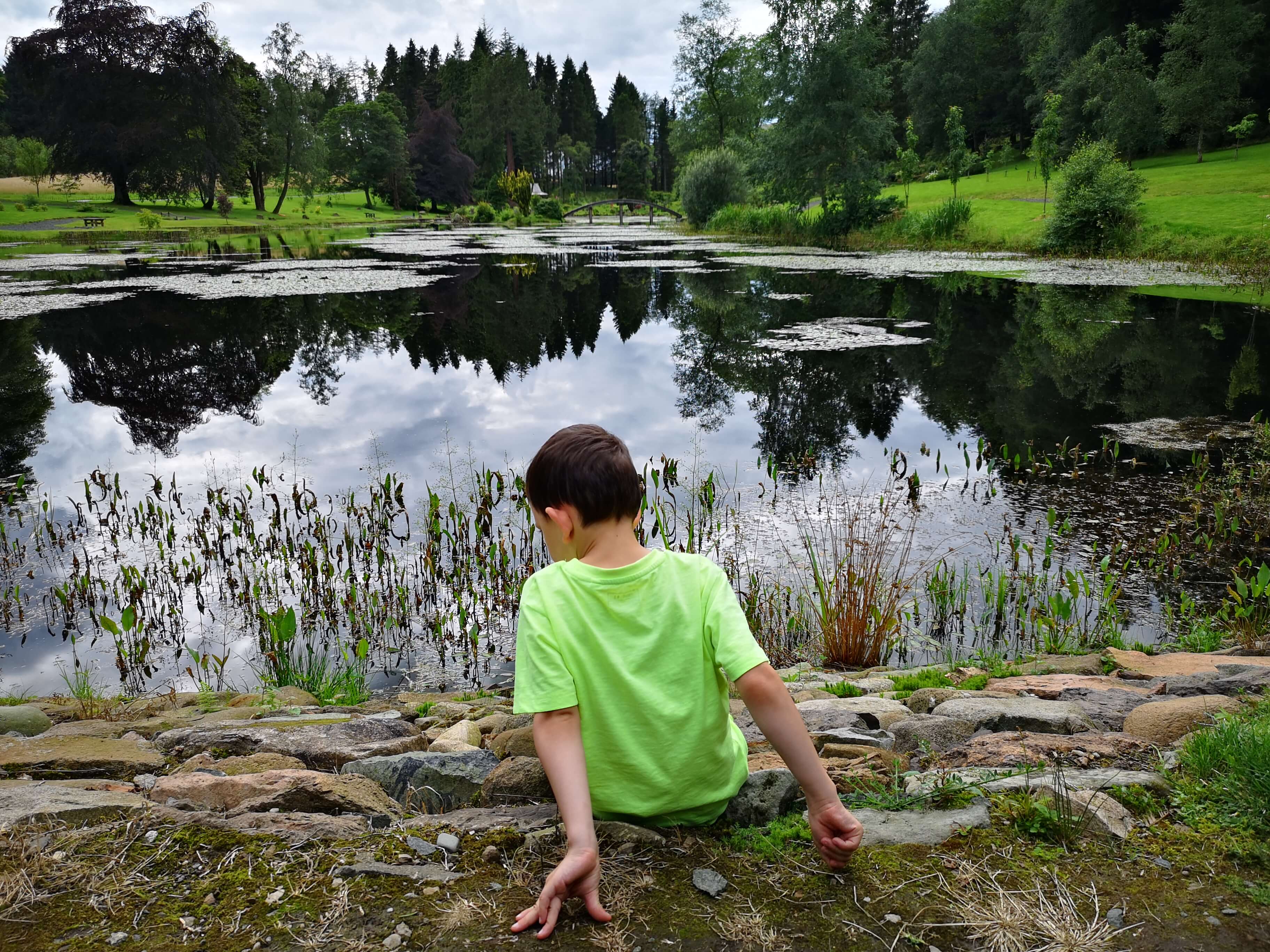 Emma's nephew sitting down beside the pond.