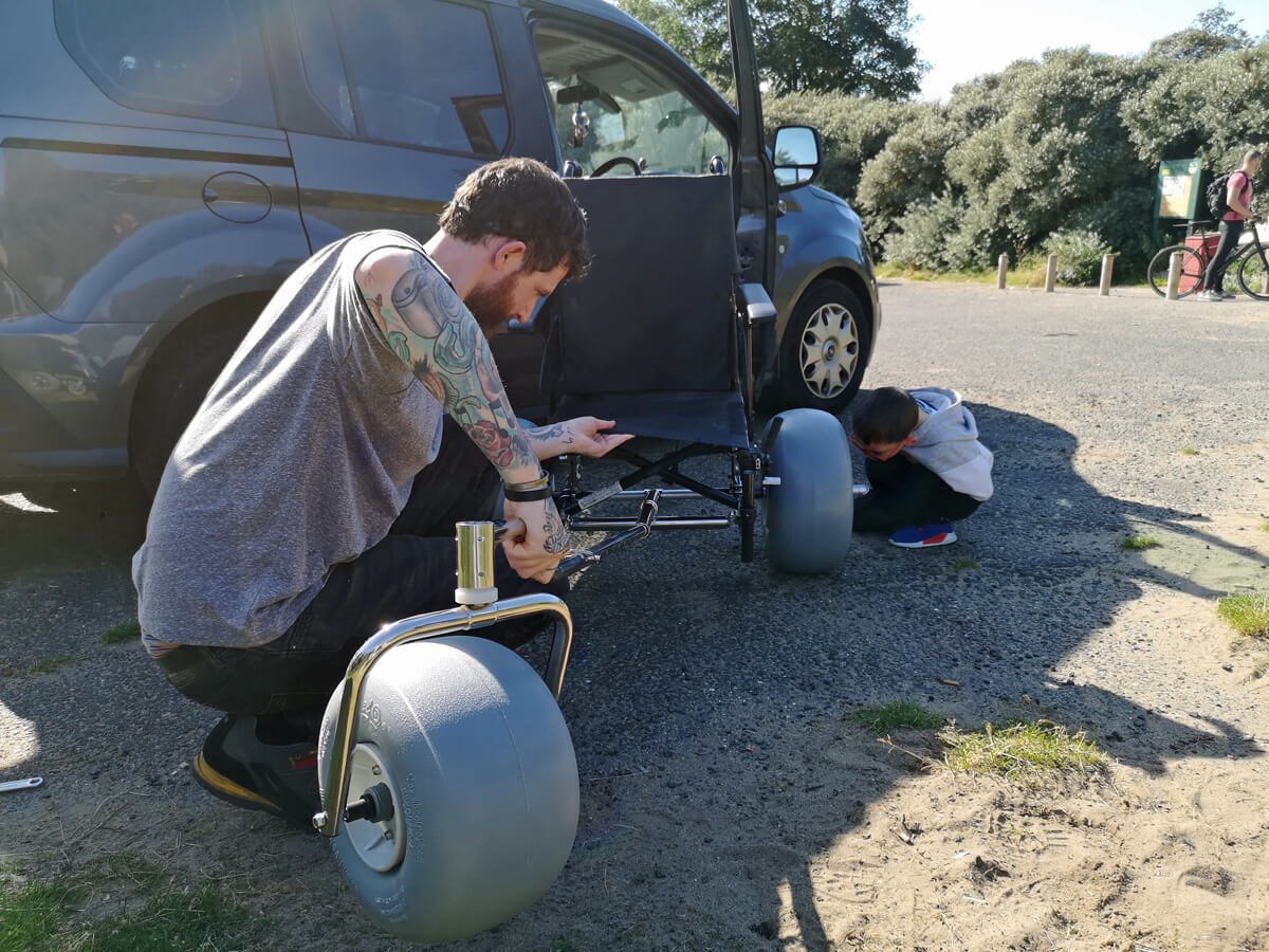 Allan and little boy (nephew) are setting up the beach conversion kit to Emma's manual wheelchair.