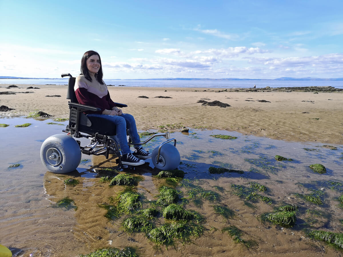Emma sitting in the WheelEEZ® Beach Wheelchair Conversion Kit.