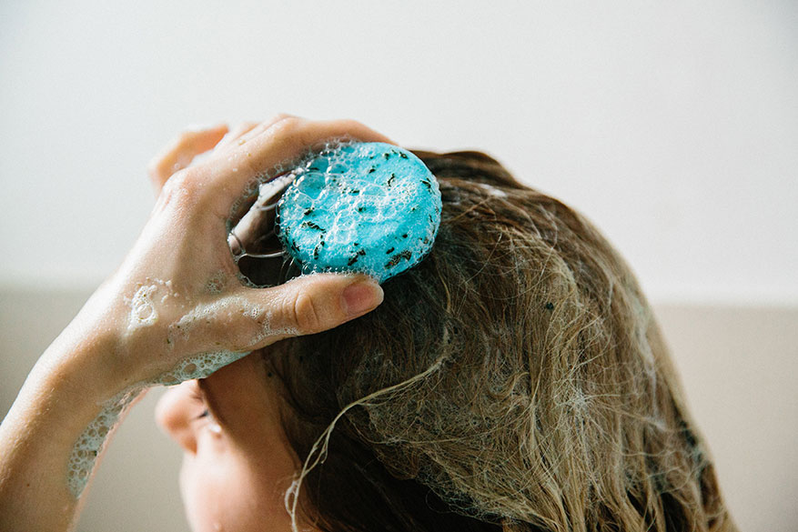 Lush Seanik Shampoo Bar being applied and rubbed into a womans hair.