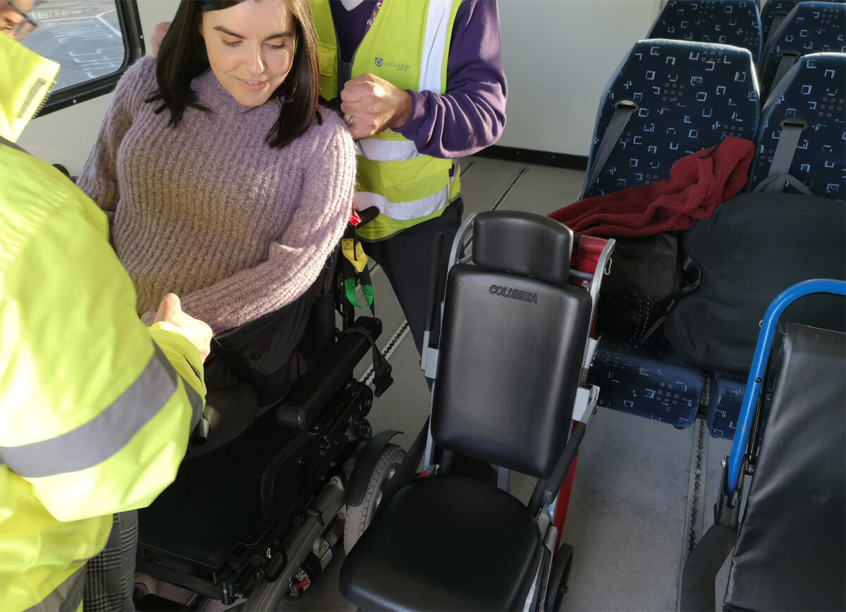 Emma being lifted out of her wheelchair by two special assistance workers.