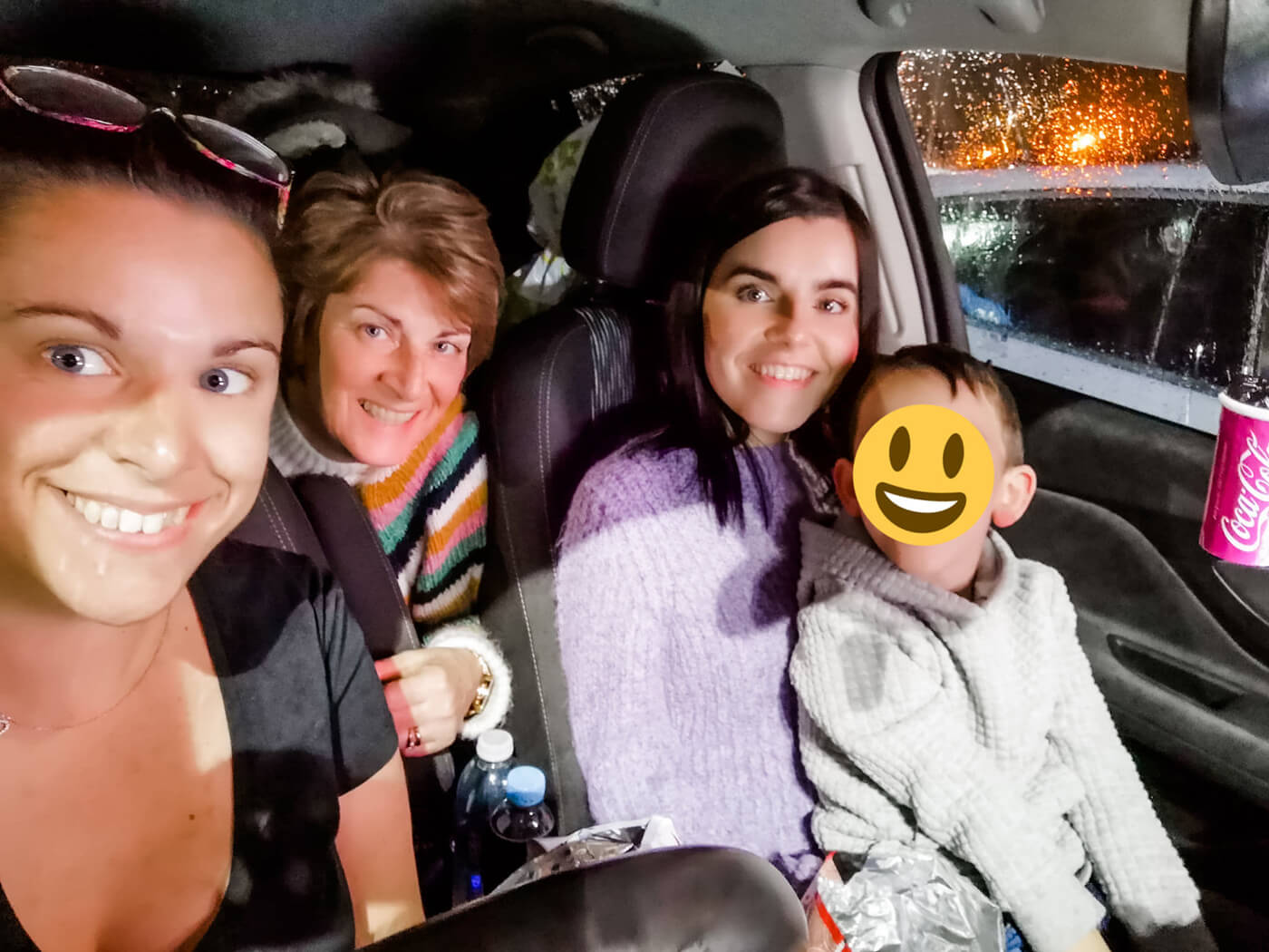 Emma sitting in the front passenger seat with her nephew on her knee. Her sister is in the drivers seat and their mum is leaning forward between them.