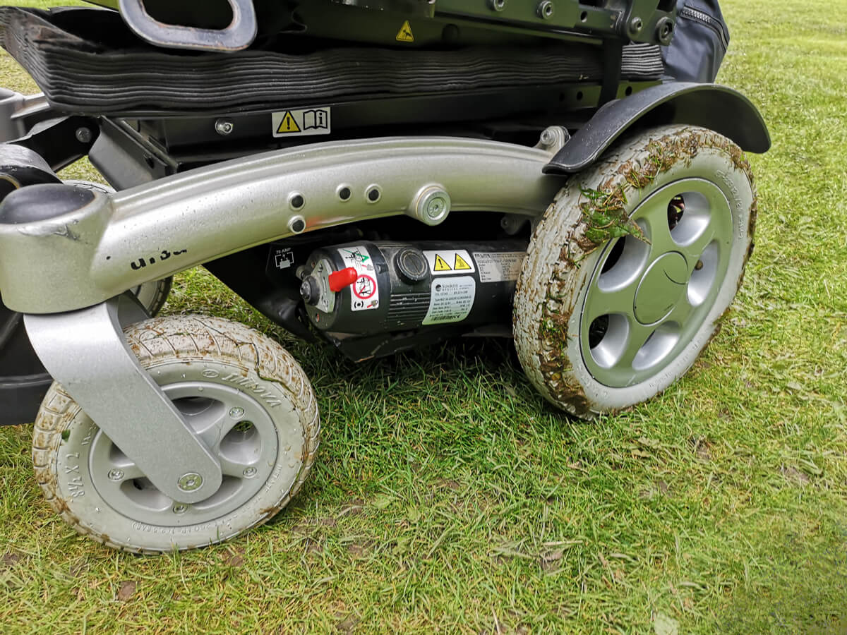 A close up of Emma's wheelchair with her wheels covered in mud.