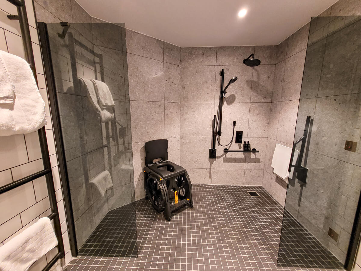 Hotel Brooklyn wheelchair accessible bathroom with roll-in shower and WheelAble Folding Shower Commode Chair.