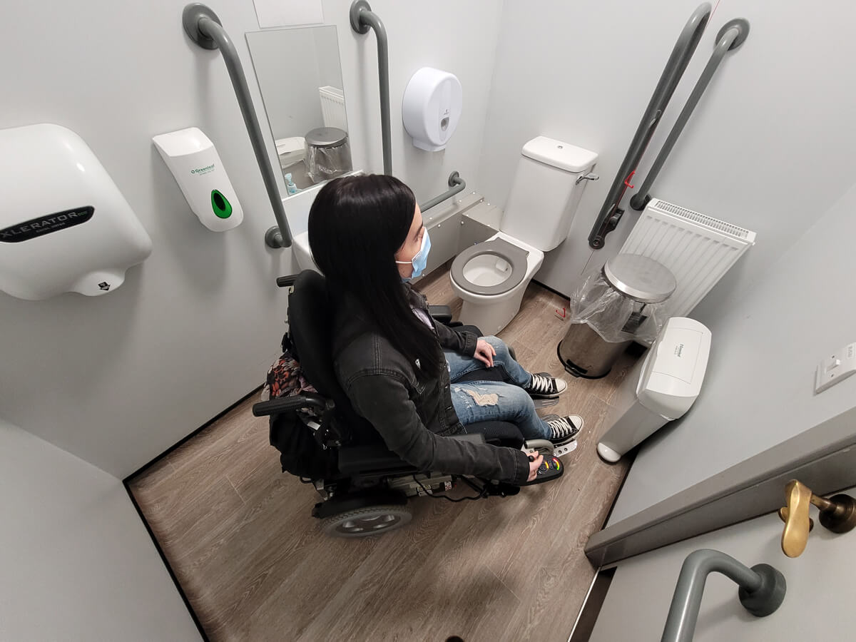 Emma sat in her power wheelchair inside the accessible toilet at Arnotdale House & Cafe Falkirk.