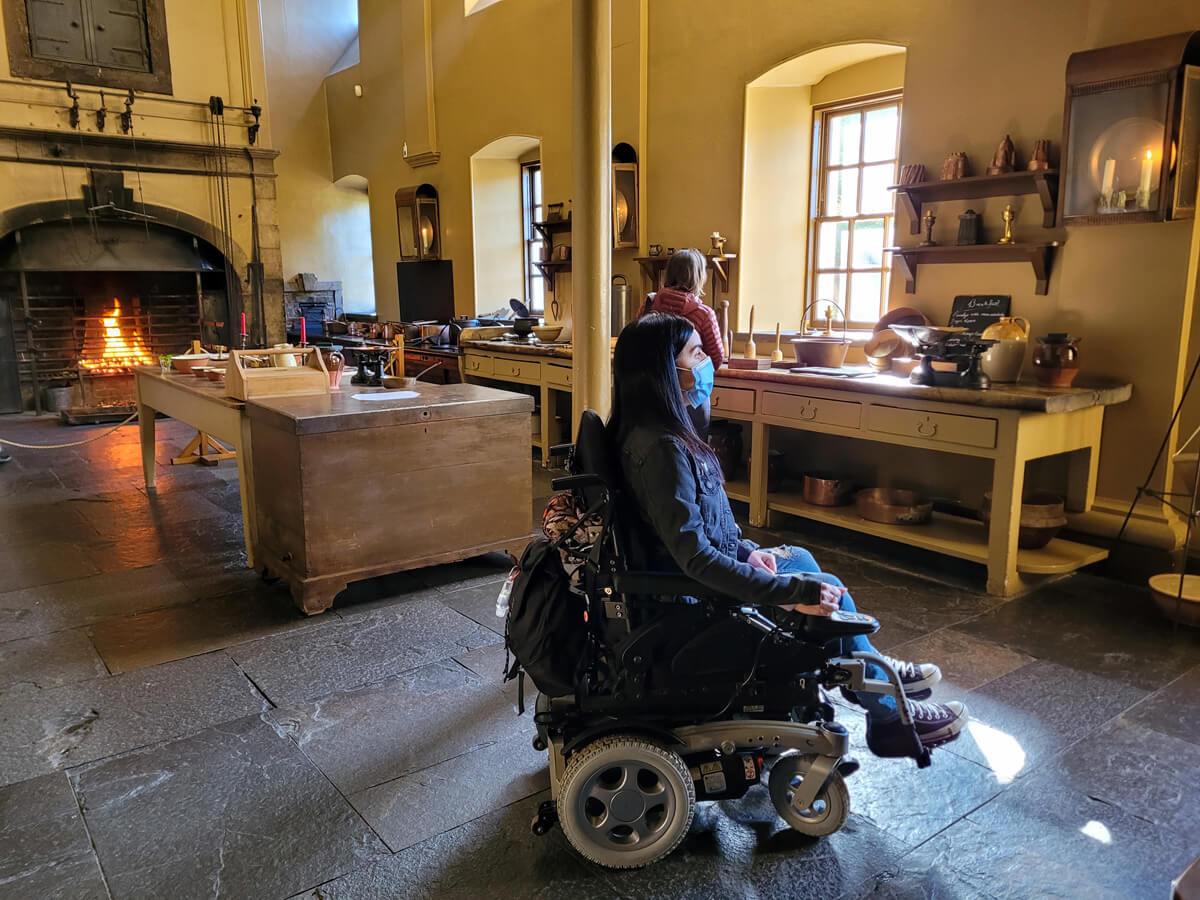 Emma sat in her wheelchair in the Georgian kitchen at Callendar House. Emma is pictured side-on and she is looking off to the right.