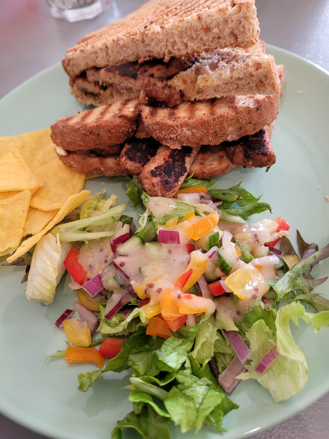 A plate with vegan sausage sandwich and salad.