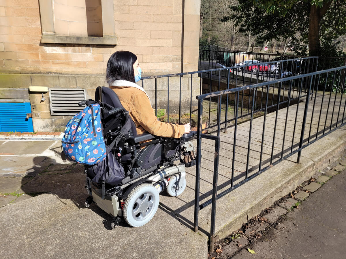 Emma driving her wheelchair up at wheelchair access to enter the Smith Art Gallery and Museum