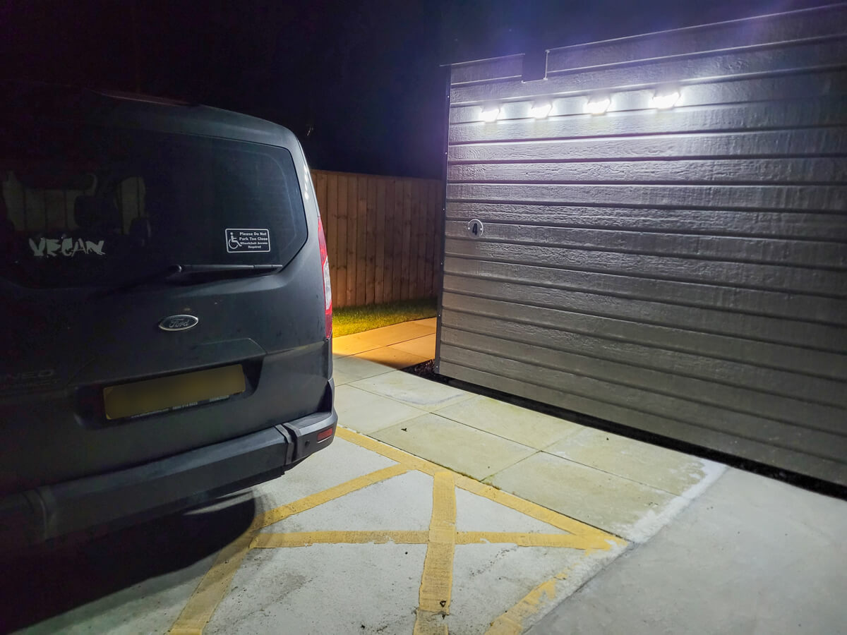 A wheelchair accessible vehicle parked in a disabled parking bay next to a glamping pod.