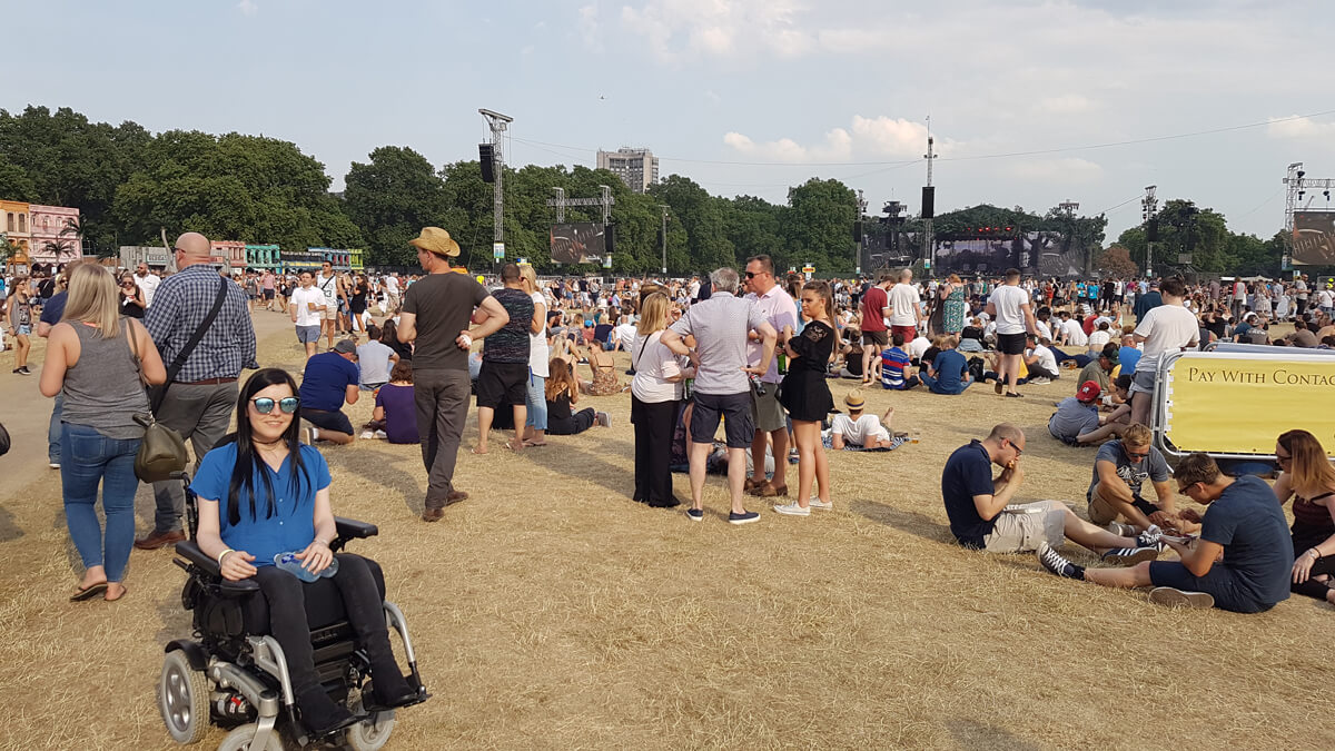 Emma, a wheelchair user at BST Hyde Park festival. She is sitting in the park surrounded by other people