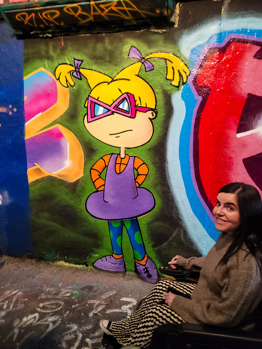 Emma posing next to Angelica from the Rugrats spray painted on a wall inside Leake Street Arches