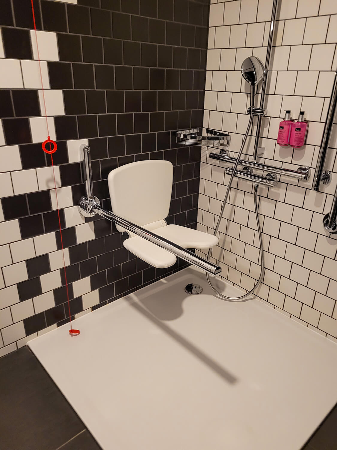 A roll-in shower and wall mounted shower seat at the Moxy Manchester City hotel.