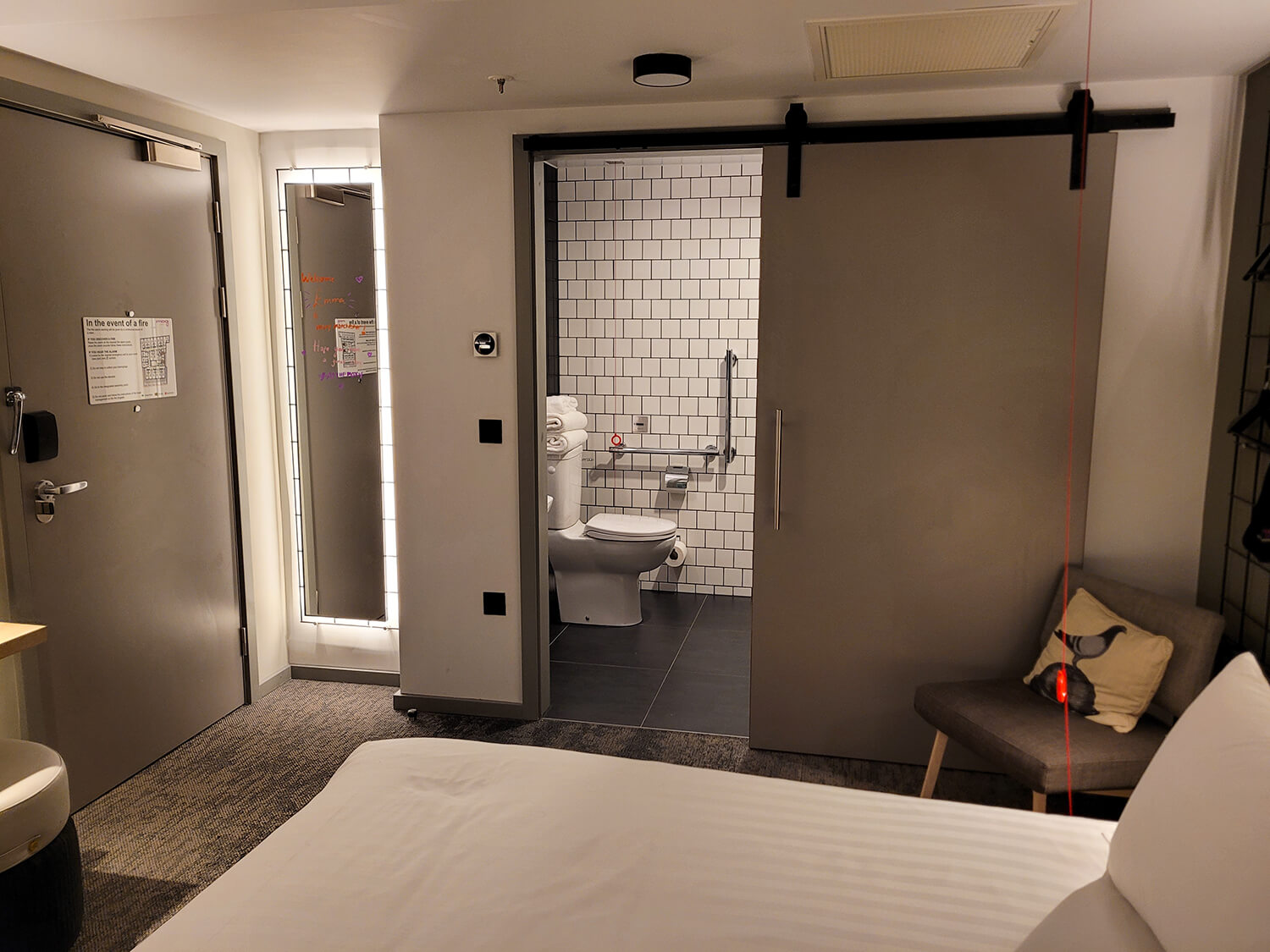 A view looking across the accessible room to the wetroom bathroom which has a sliding barn door at the Moxy Manchester City hotel.