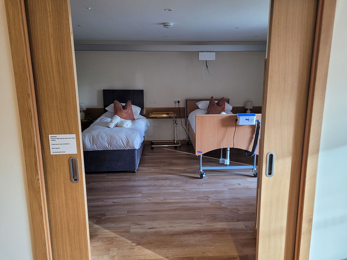 The accessible twin room with a height adjustable profiling bed with an Invacare pressure relief air mattress. Plus a single divan bed. Ceiling track hoist above the beds.