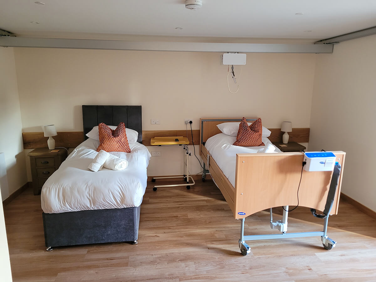 The accessible twin room with a height adjustable profiling bed with an Invacare pressure relief air mattress. Plus a single divan bed. Ceiling track hoist above the beds.