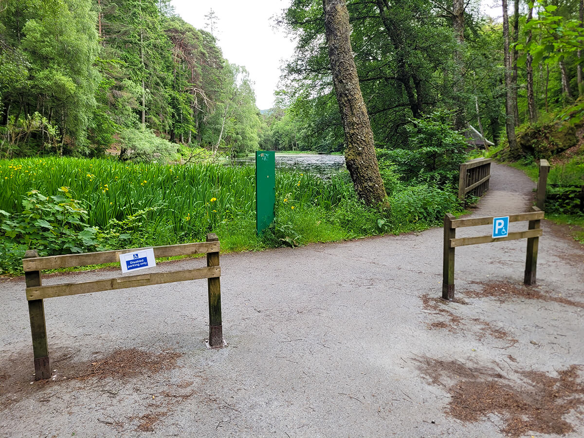 Two wooden parking posts with disabled parking signs next to the Loch Dunmore trail