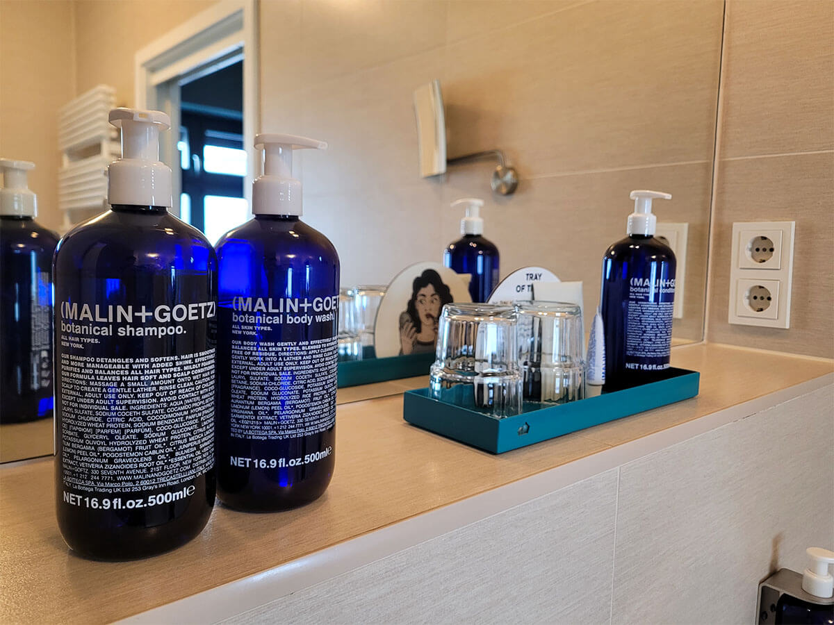 skincare and haircare products by MALIN+GOETZ displayed on a bathroom shelf.