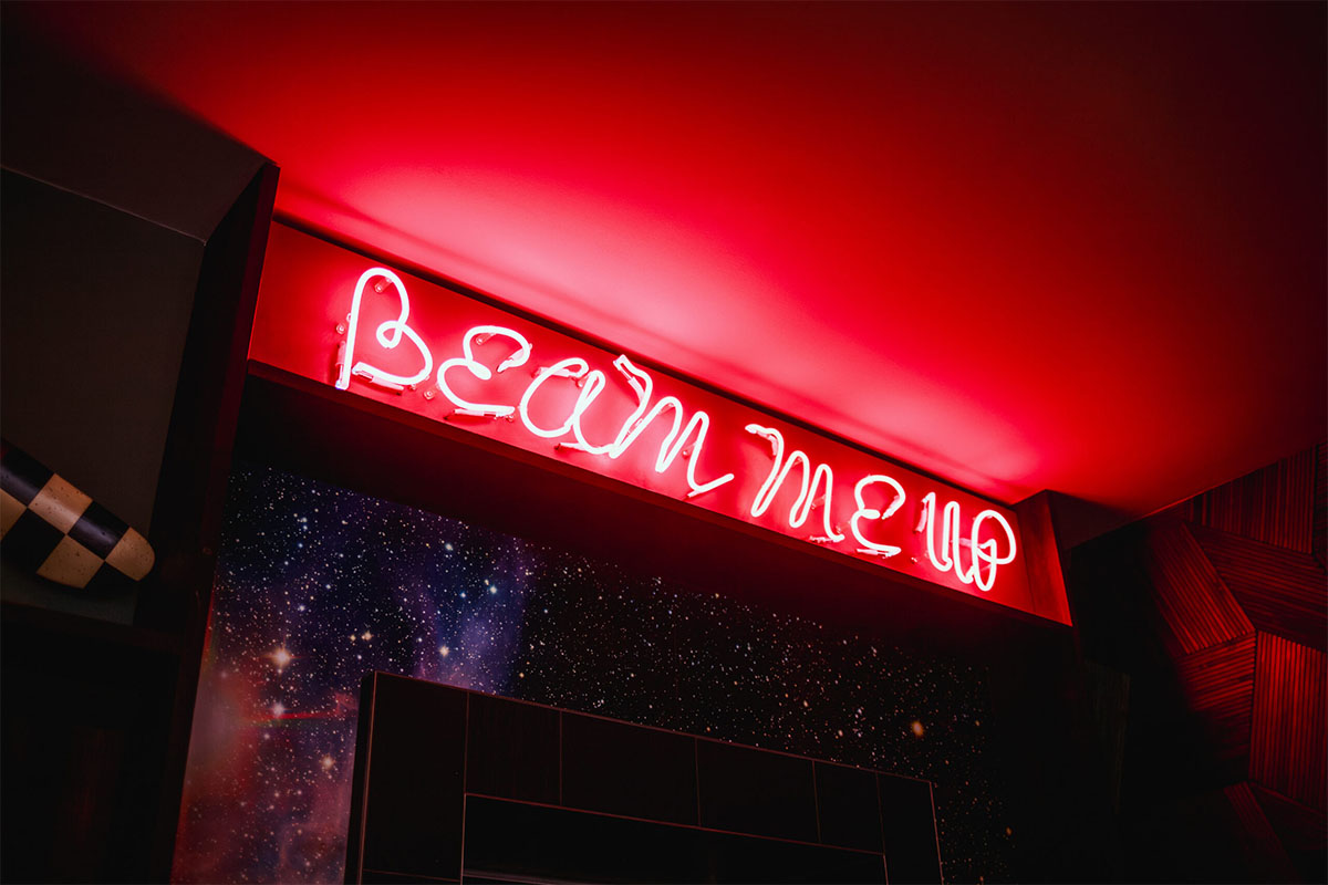 beam me up” neon sign above the lift doors