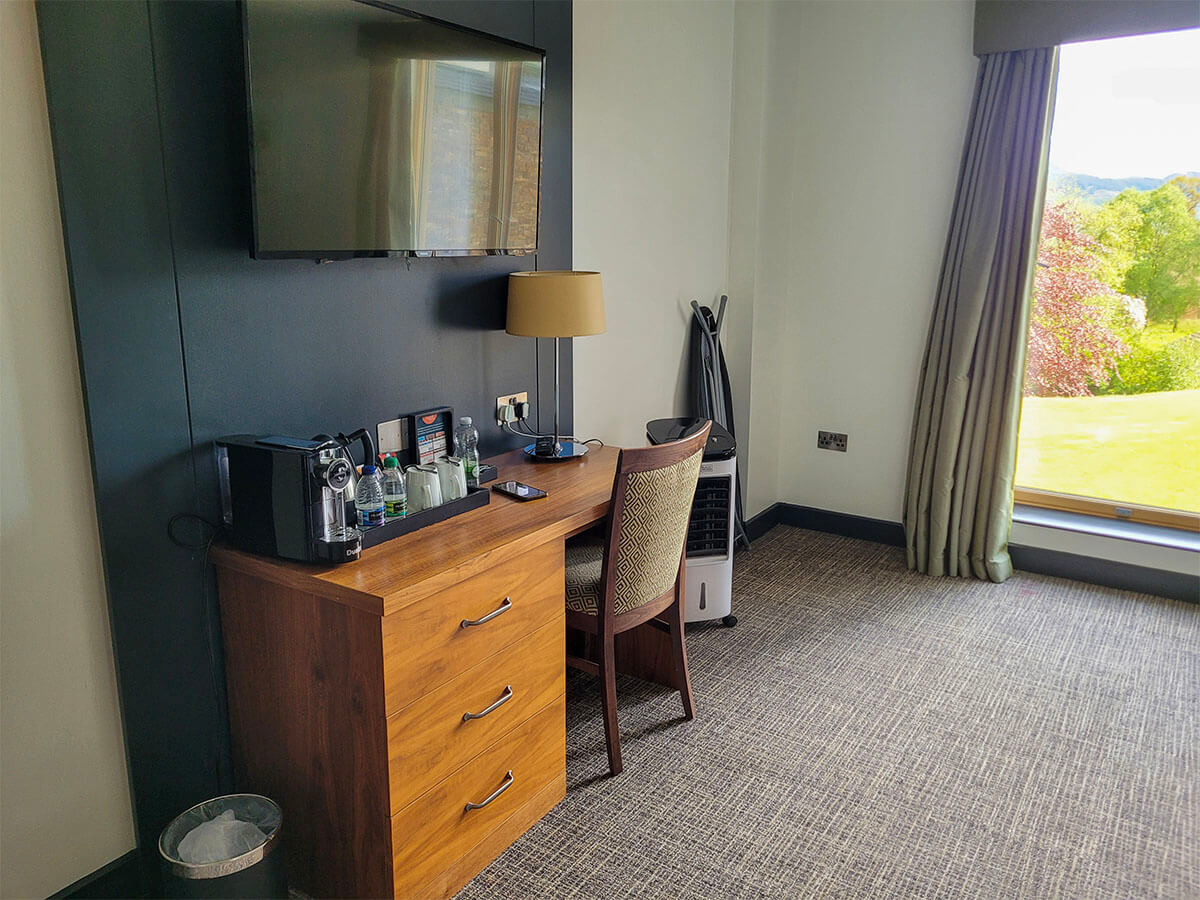 A wall mounted TV and desk in a room at the Drimsynie Estate Hotel room