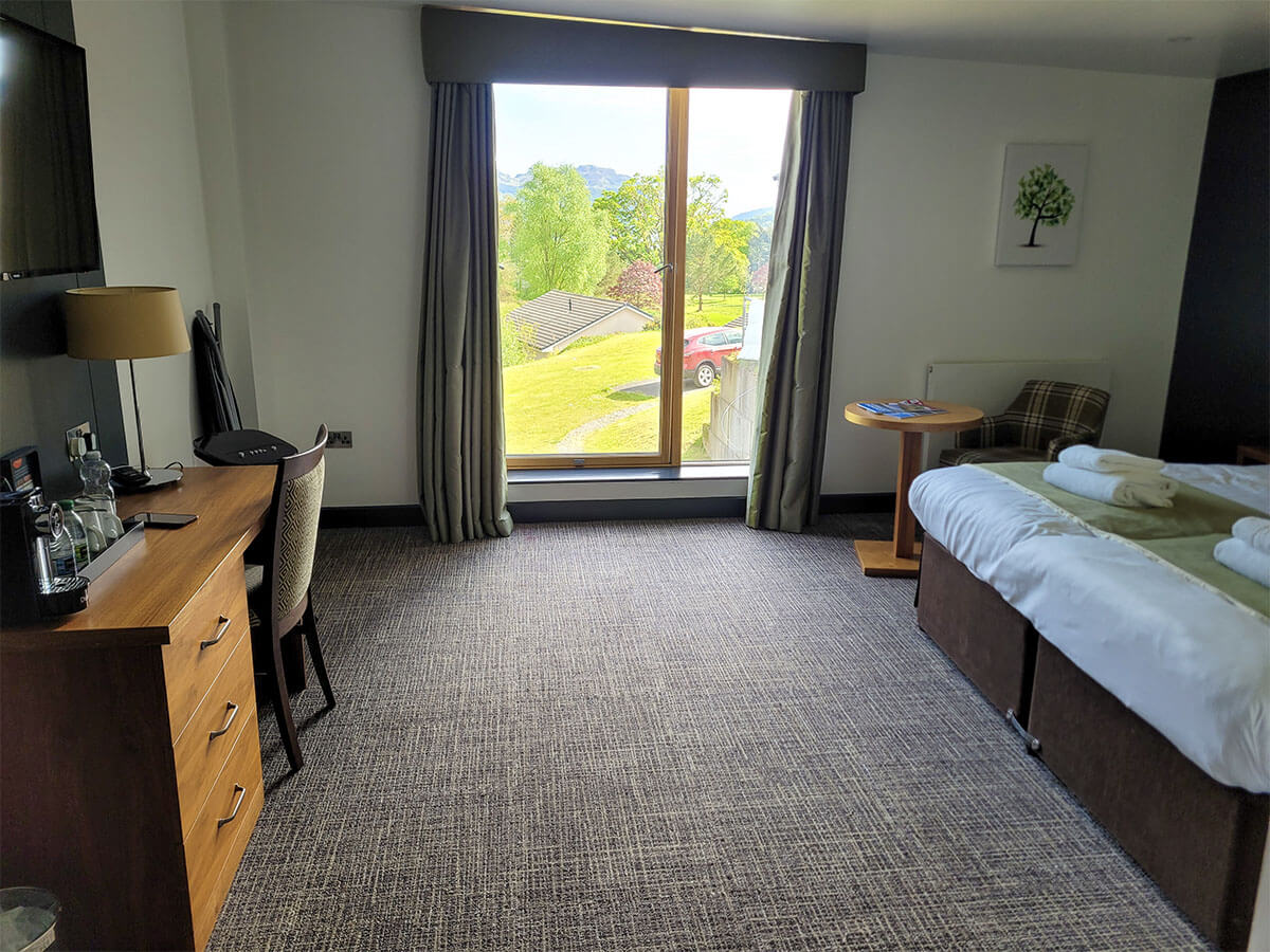 a large floor to ceiling window in the wheelchair accessible room at the Drimsynie Estate hotel with loch and mountains views