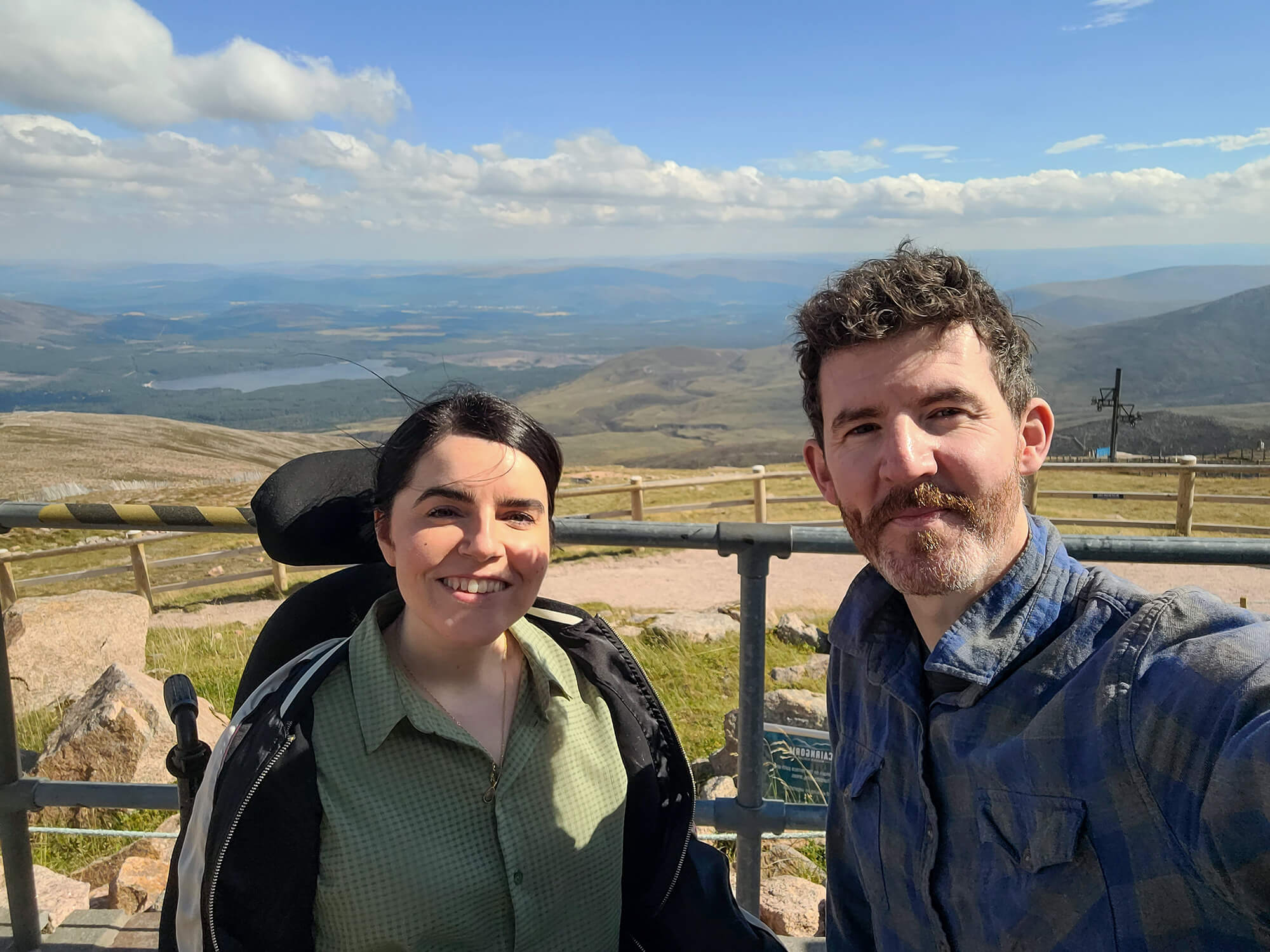 Emma and Allan at the top of the Cairngorm Mountain Resort with a stunning view of the mountains and Loch Morlich in the background