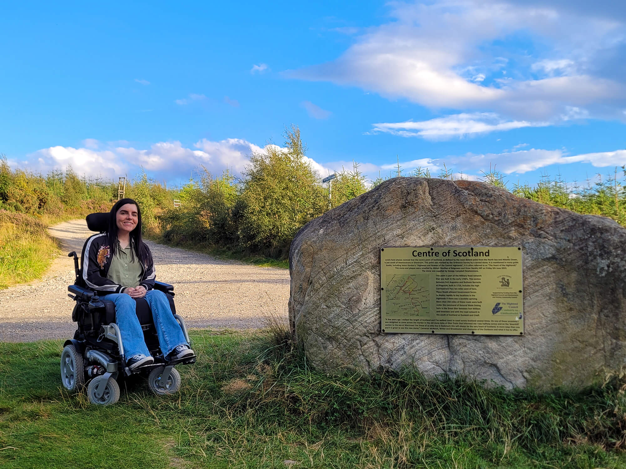 Emma sat in her wheelchair next to The Centre of Scotland Stone in Glen Truim, near the village of Newtonmore.