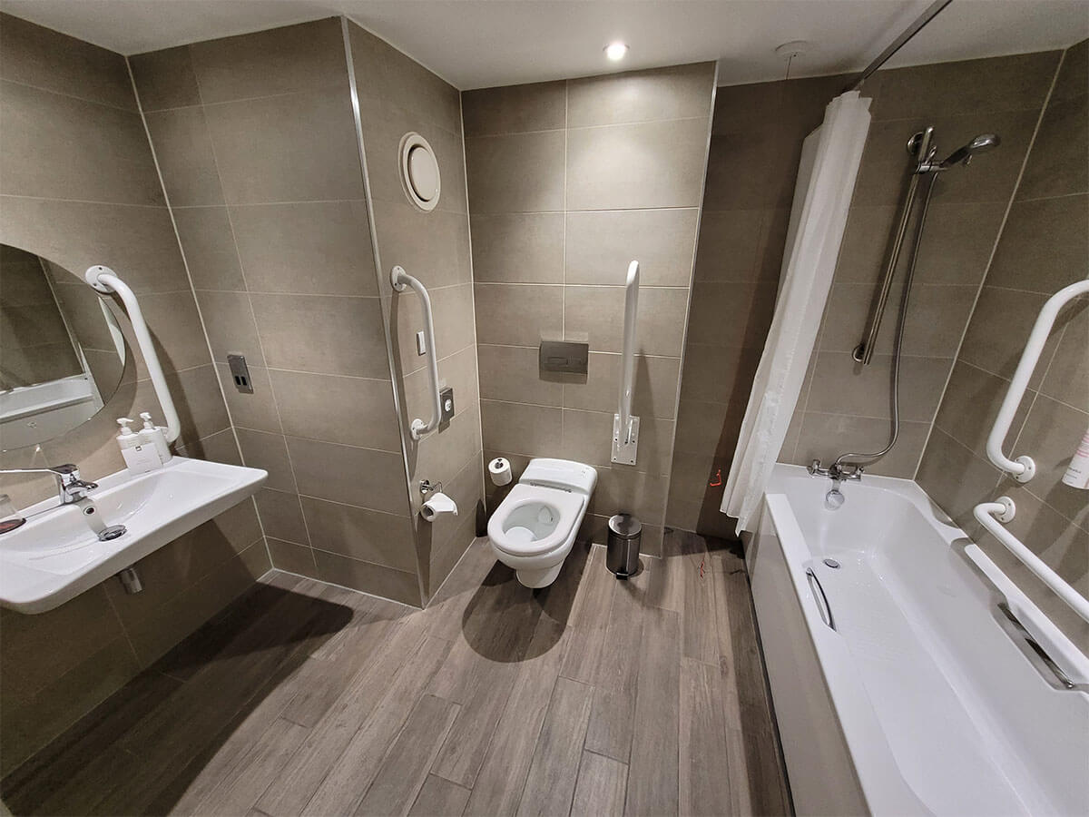 A bathroom with a bathtub in the wheelchair accessible room at Manchester Marriott Victoria & Albert Hotel. The photo shows the sink, toilet and bathtub.