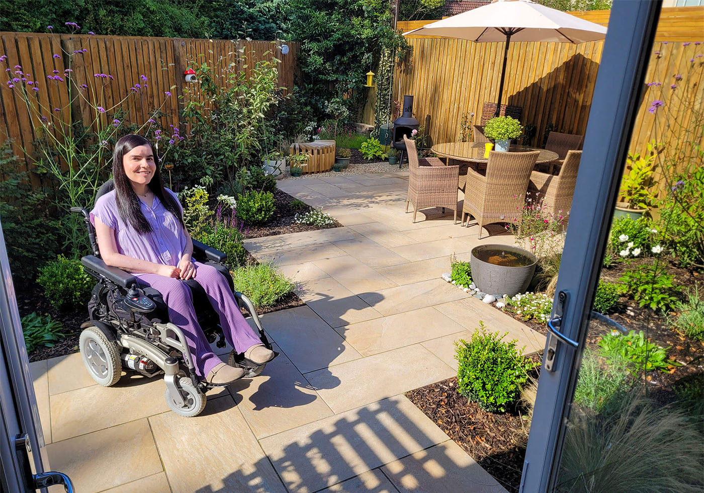 Emma, a wheelchair user, sitting in her wheelchair accessible garden after it's been transformed into a green sanctuary.