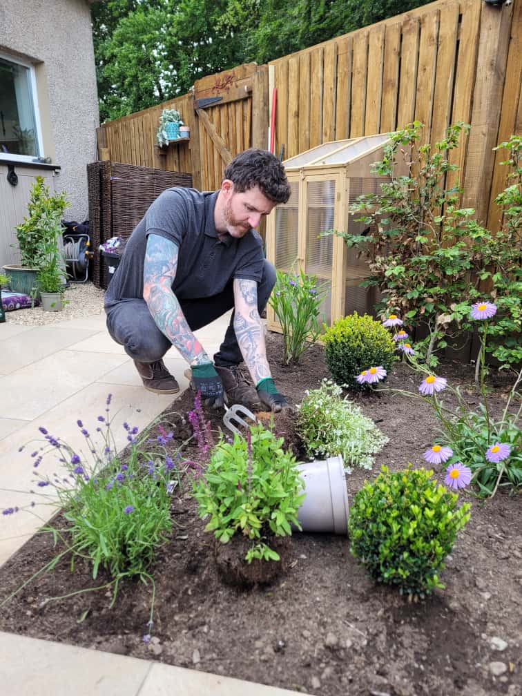 Allan planting shrubs and flowers in the garden