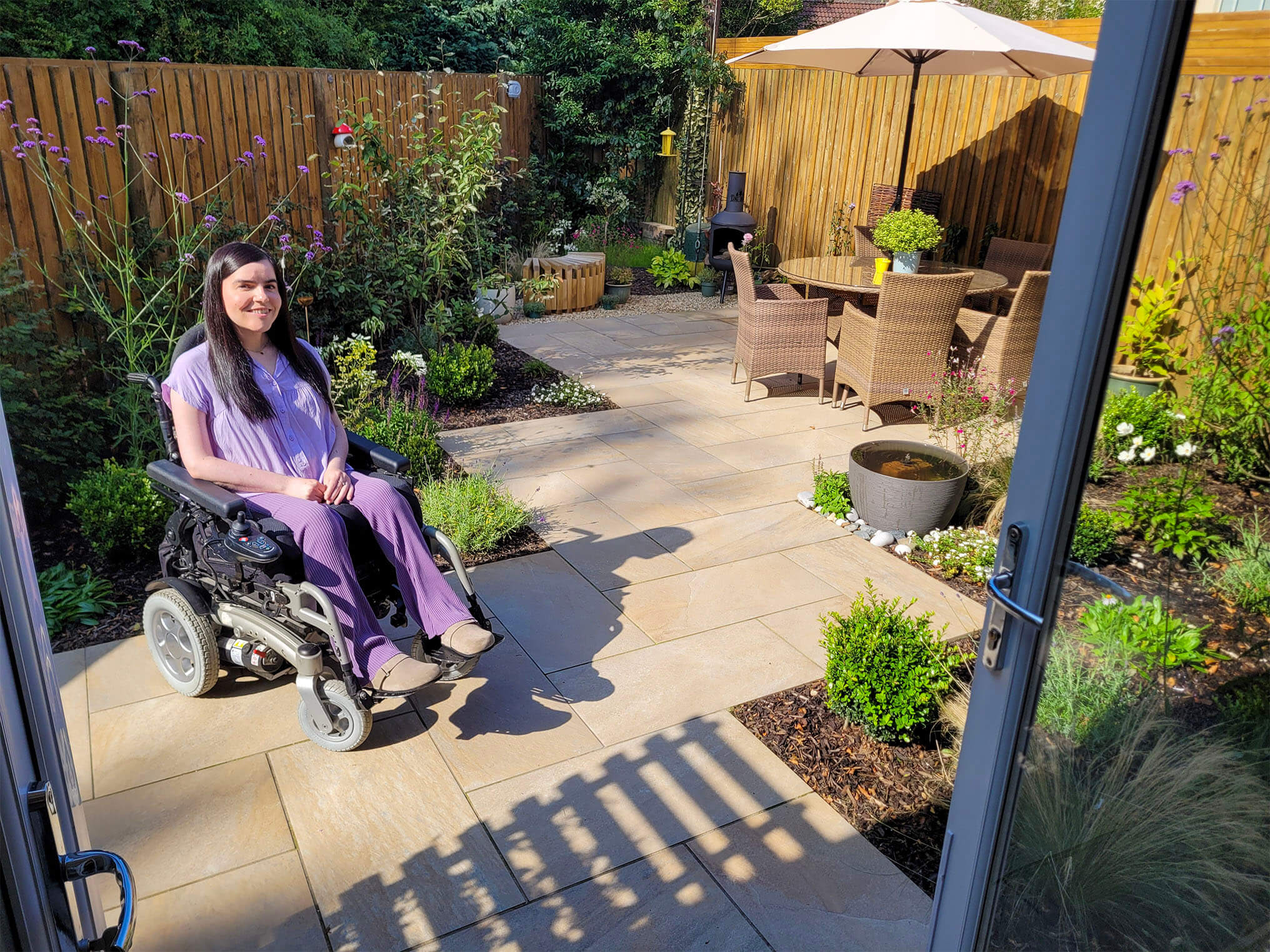 Emma, a wheelchair user, sitting in her wheelchair accessible garden after it's been transformed into a green sanctuary.