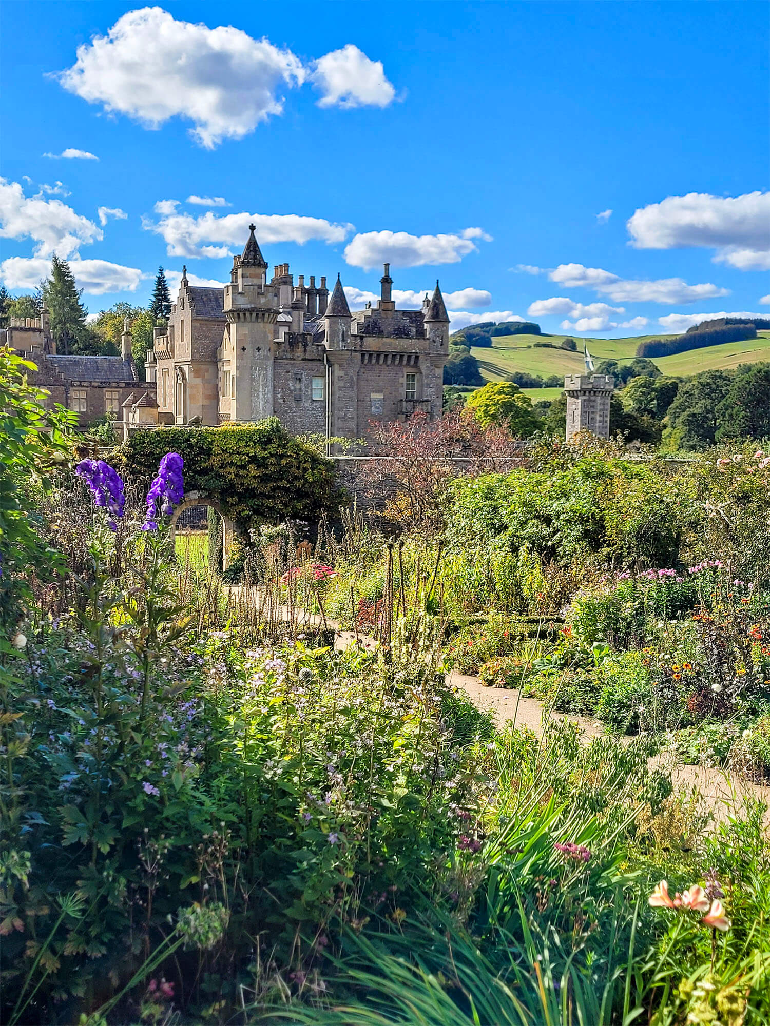 Abbotsford House, conundrum castle in the background looking like a fairytale castle while the garden and flowers are in the foreground.