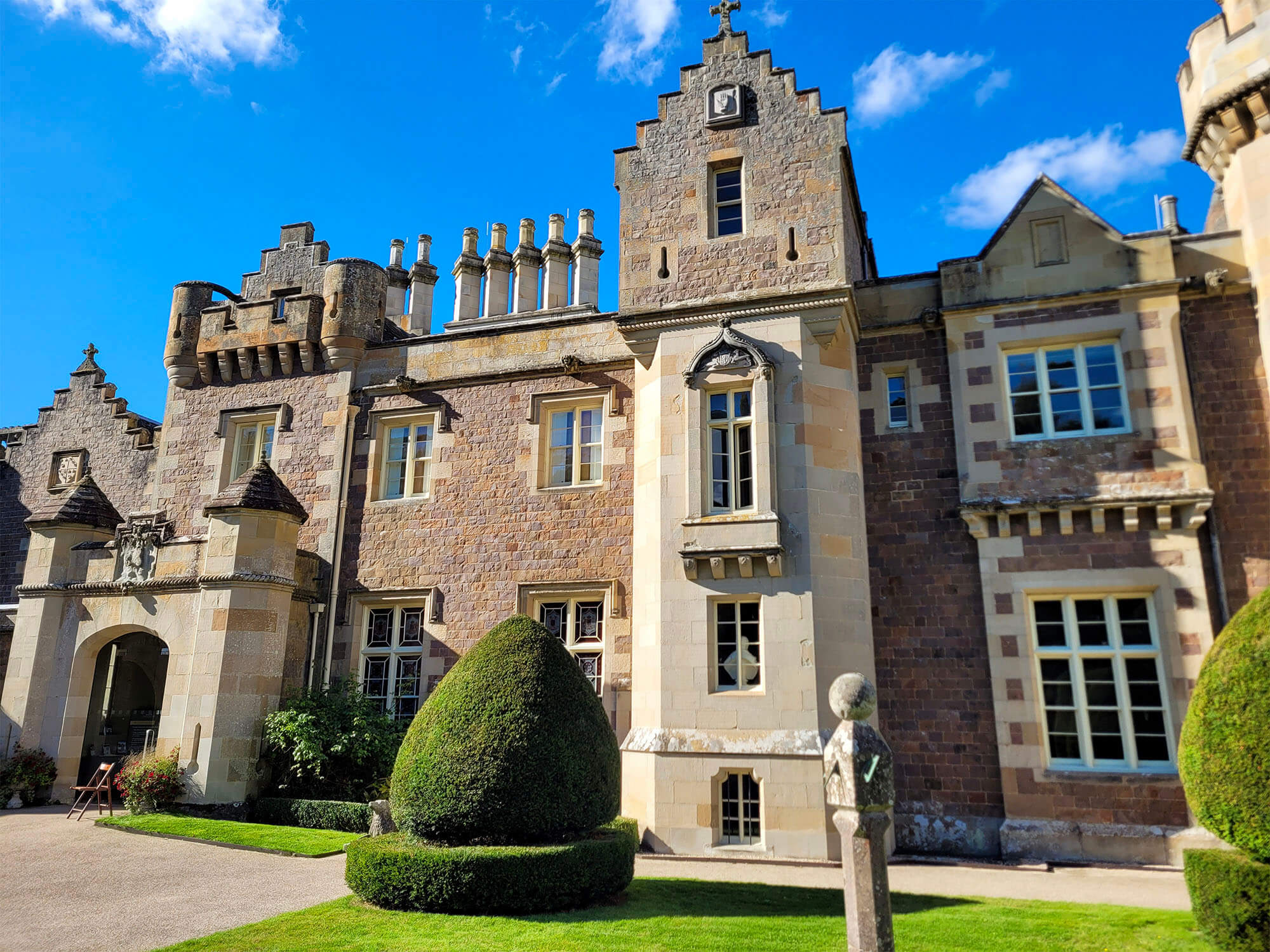 The exterior of Abbotsford House, the home of Sir Walter Scott, on a sunny day with blue sky.
