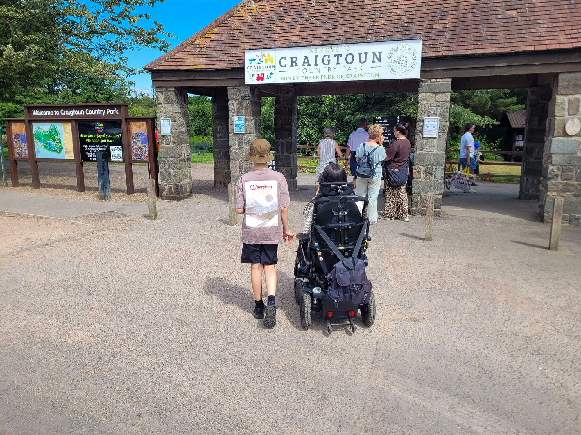 Emma, a wheelchair user entering Craigtoun Country Park with her nephew walking at her side.