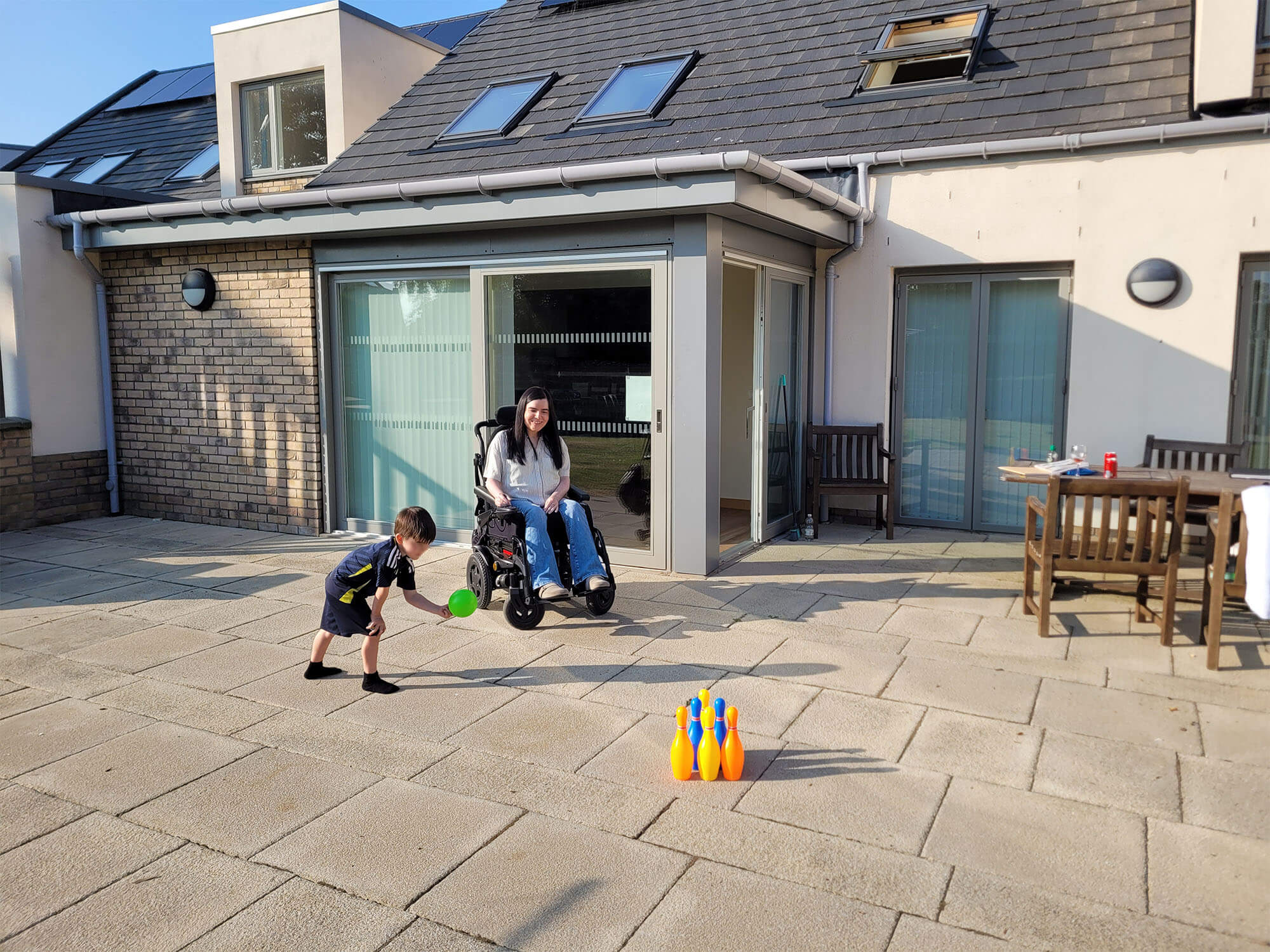 Emma and her young nephew a bowling game outside on the patio at the Largo lodge at Homelands Trust.