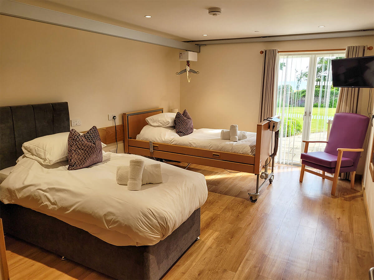 The accessible twin room with a height adjustable profiling bed with an Invacare pressure relief air mattress. Plus a single divan bed. Ceiling track hoist above the beds.