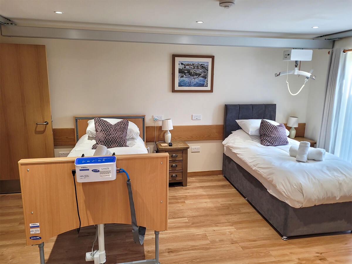 The accessible twin room with a height adjustable profiling bed with an Invacare pressure relief air mattress. Plus a single divan bed. Ceiling track hoist above the beds.