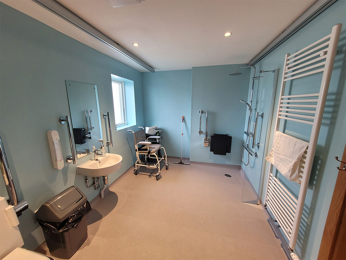 Wet room with roll-in shower, ceiling track hoist, closomat toilet at Homelands Trust in Fife.