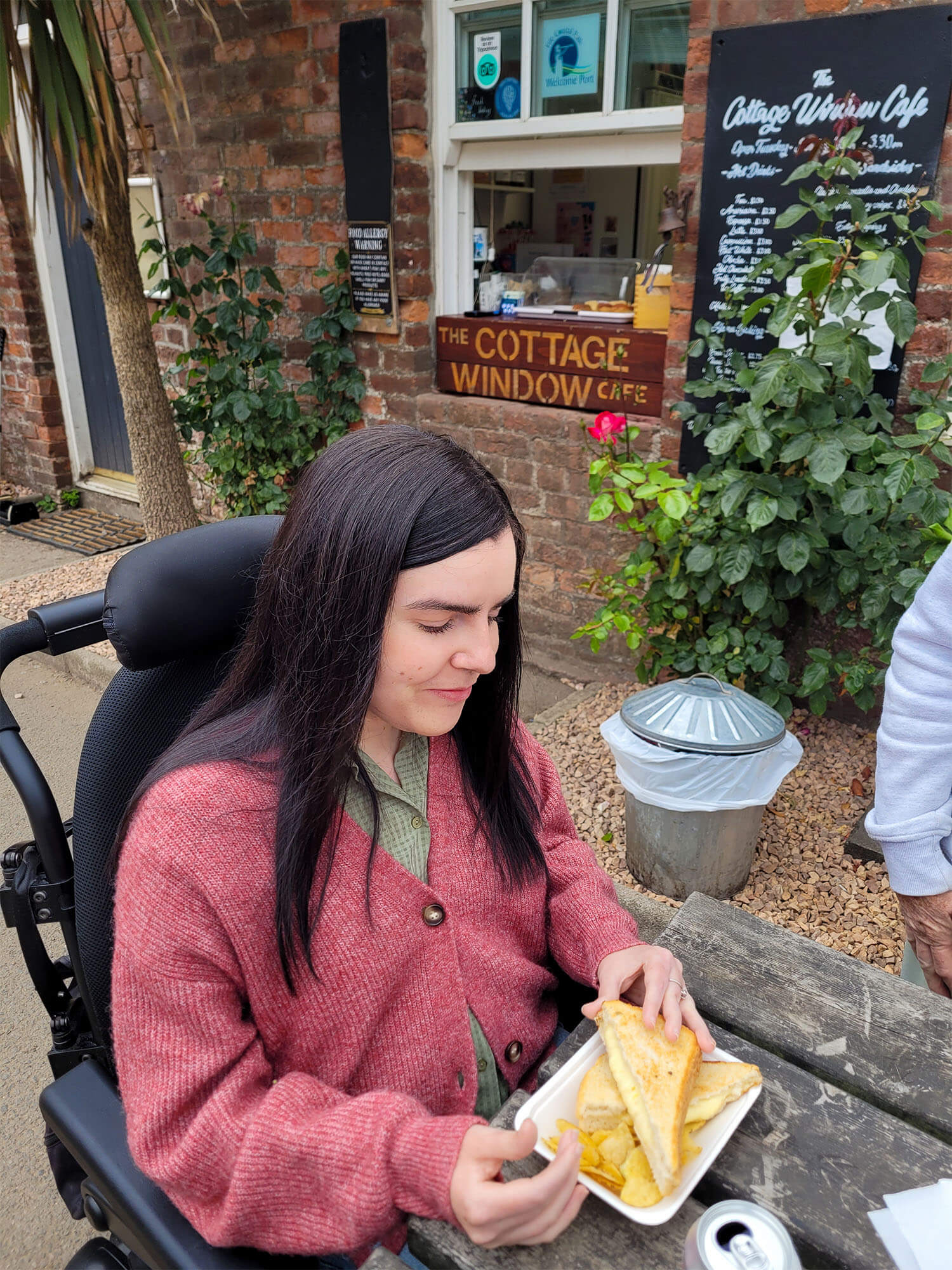 Emma sat eating a cheese toastie from The Cottage Window Café in Silverburn Park, Fife.