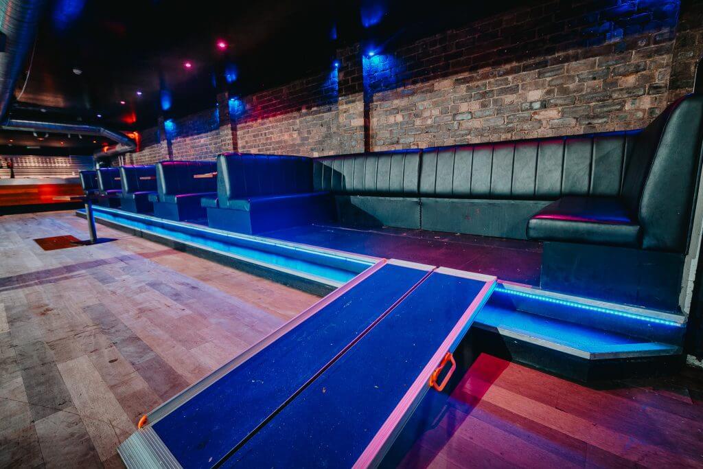 A large seated booth with two steps and a portable ramp.